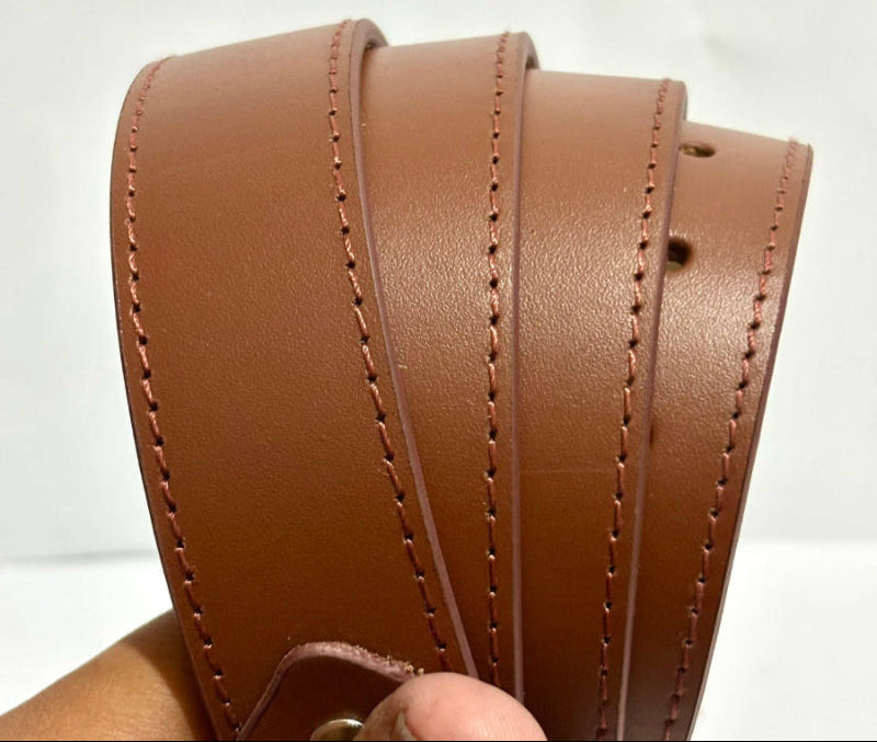 Close-up of a brown leather strap with visible stitching on a plain background.