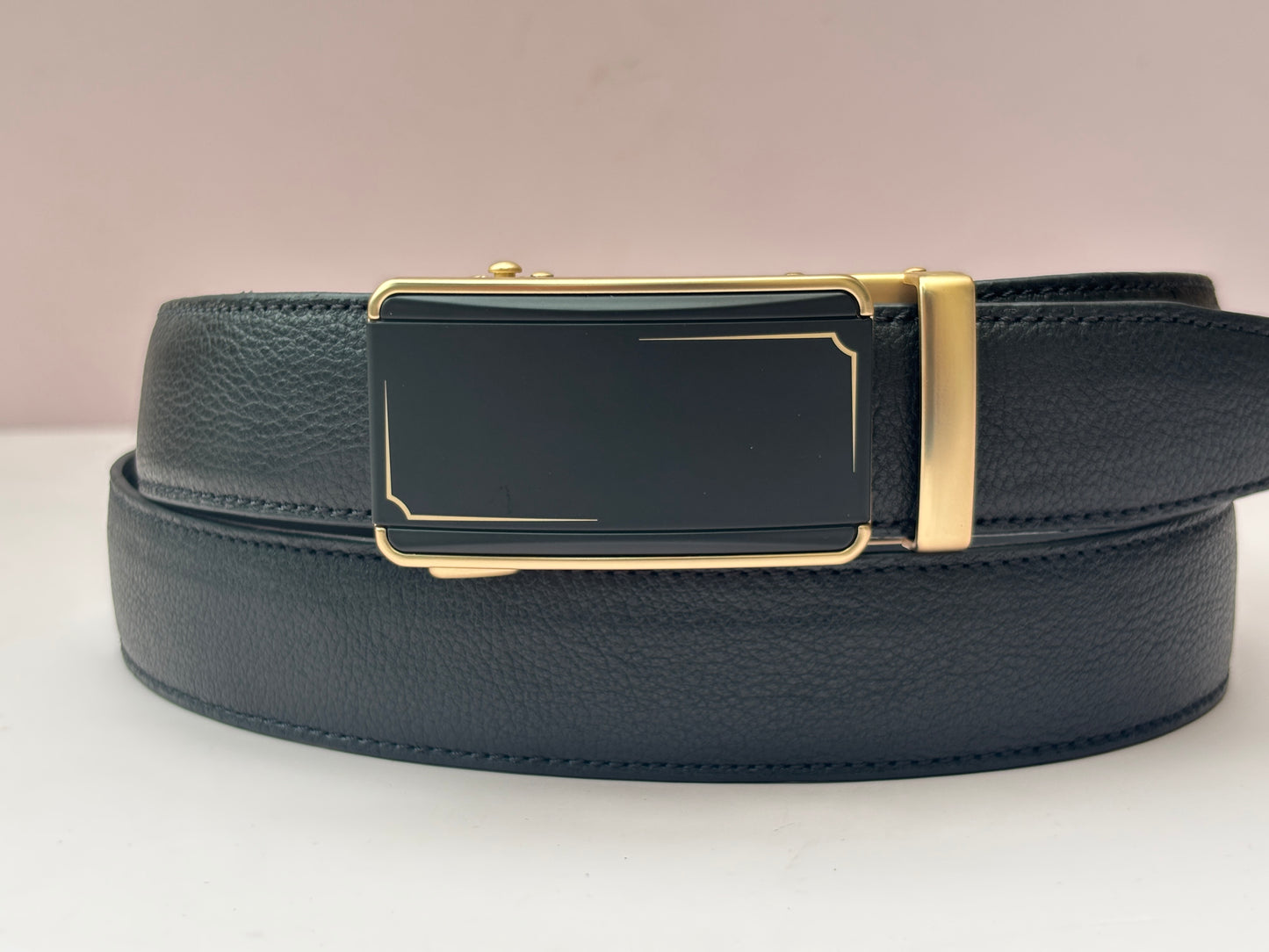 Black leather belt with a gold buckle on a light background