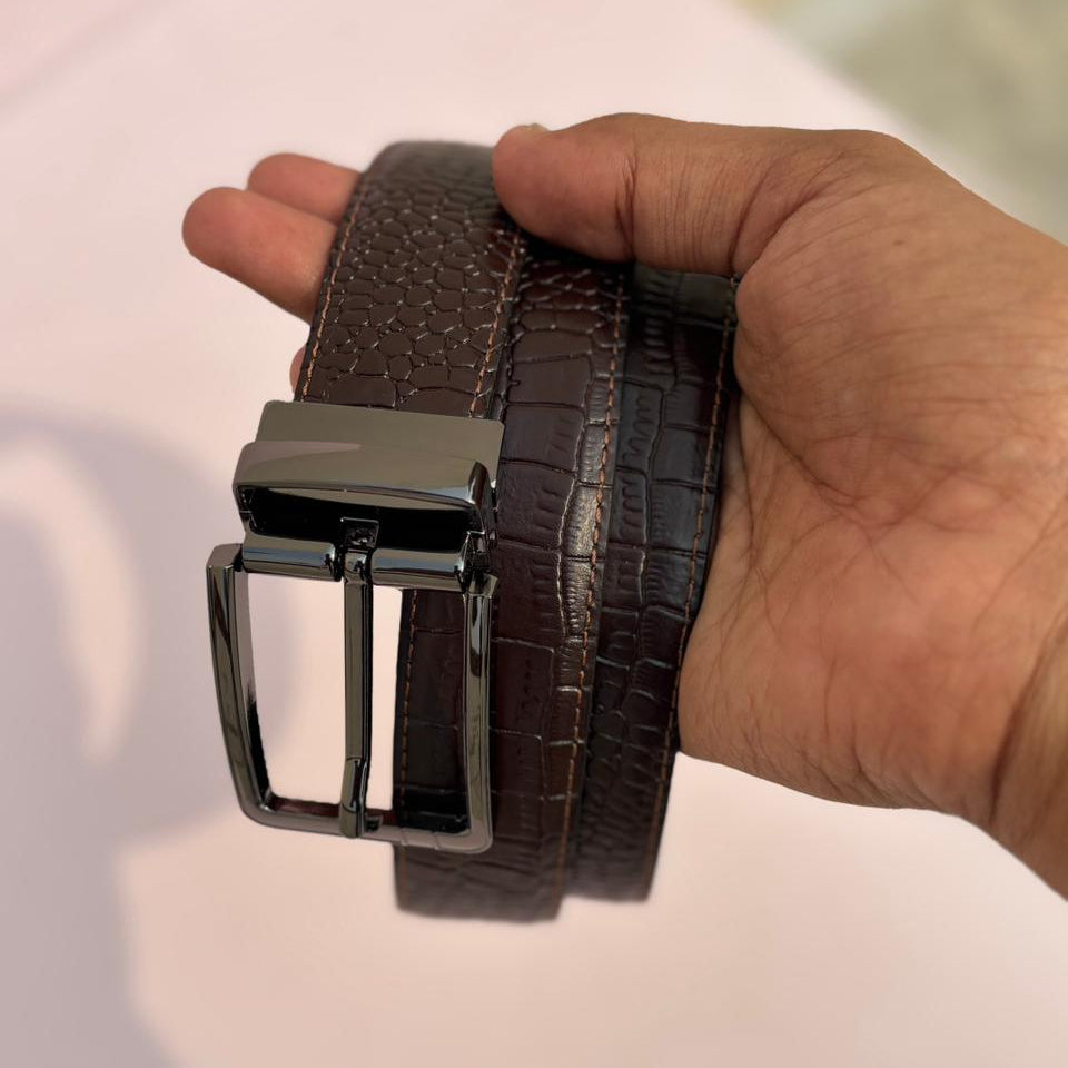 Brown belt with a silver buckle held by a hand on a light background