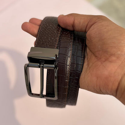 Brown belt with a silver buckle held by a hand on a light background